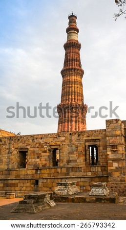 Grave markers with a stone wall and the qutub minar at the back. Shows the rear compound of the Minar