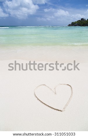 The shape of a heart in the sand of a clean white beach with turquoise water