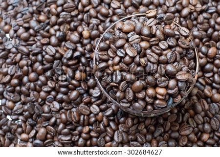 Coffee beans in cup, on pile of coffee beans, Select focus