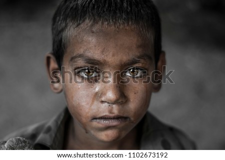 closeup of a poor staring hungry orphan boy in a refugee camp with a sad expression on his face and his face and clothes are dirty and his eyes are full of pain 商業照片 © 