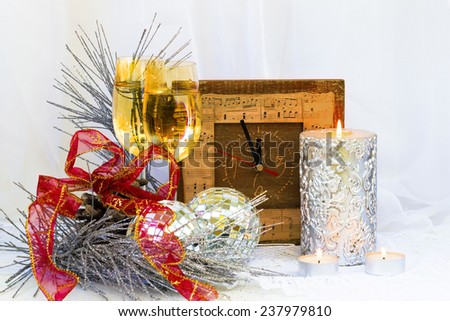 Christmas composition with clock, glasses and a thick silver candle,red bow  and Christmas tree balls