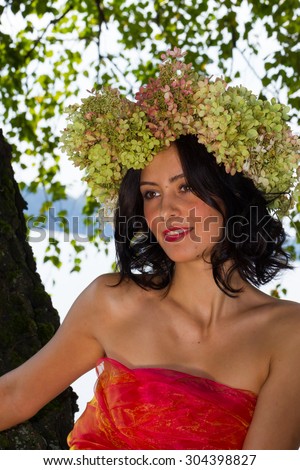 young Russian woman on her head a wreath of flowers hydrangeas, a woman relaxed, reclining on a tree trunk, happy, Russian traditions and folk life, lifestyle and clothing, intimate nature,
