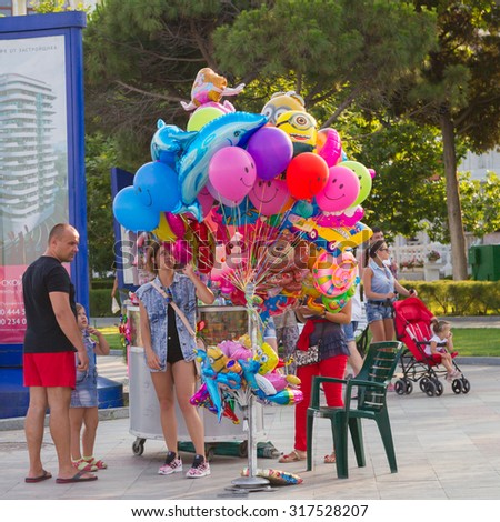 Russia, Crimea, Yalta, July 8, 2015 - saleswoman of balloons offering their wares on the waterfront of the seaside city of Yalta. Bright balloons, passersby and customers. Summer resort flavor.