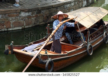 Tongli, China - July 21, 2007: A boat woman transports tourists in her traditional wooden boat in ancient Tongli watertown,  Jiangsu province, China on July 21, 2007.