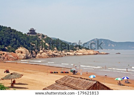 Putuoshan, China - July 19, 2007: Fragment of a  beach, East China Sea and temple in the background on Juy 19, 2009. Putuo island is an important toorists destination in the region of Shanghai.