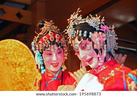 Suzhou, China - July 22, 2007: Two female actors with faces under thick layer of make-up perform chinese opera at a show for tourists in one of the gardens in Suzhou on July 22, 2007.