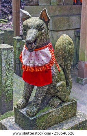 Statue of Japanese magical fox, kitsune, with a ball in its mount at a shinto shrine, Japan