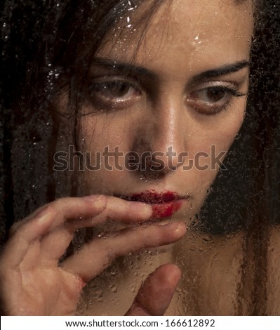 Beautiful girl looks out of the window with raindrops.