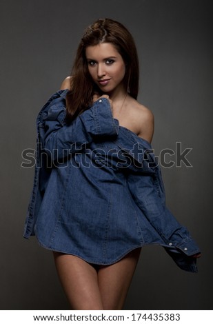 Beautiful brunette fashion model with blue shirt on a gray background.