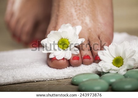 Female feet with drops of water, towel, flowers and spa rocks. Macro image.