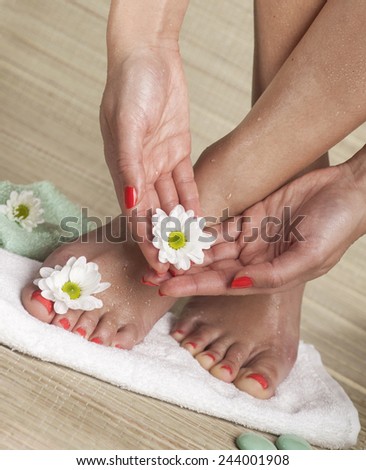 Female feet and hands with drops of water, towel, flowers and spa rocks. Copy space.