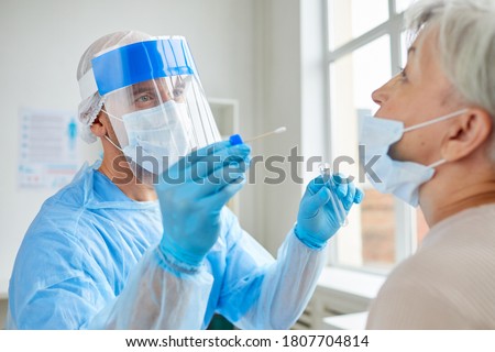 Professional medical worker wearing personal protective equipment testing senior woman for dangerous disease using test stick Photo stock © 