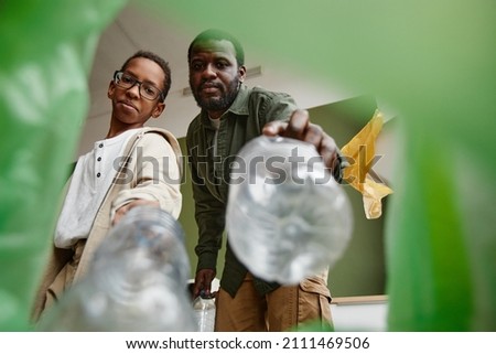 Low angle view at father and son sorting household waste at home together, recycling bin POV Stock foto © 