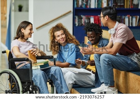Diverse group of young people chatting in college library including female student with disability ストックフォト © 