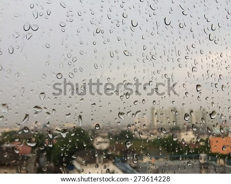 Rain drops on window surface, soft focus city view background