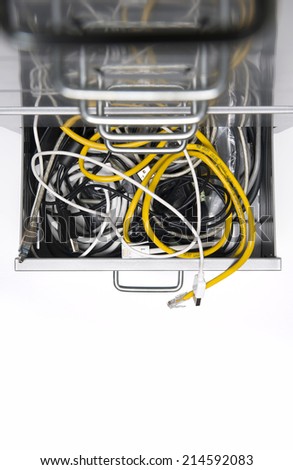 Tangle of computer cable sticking out of the draw of a filing cabinet