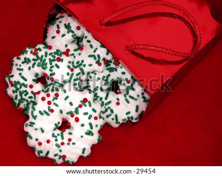 Shiny red foil bag spilling christmas gingerbread cookies out on red felt.