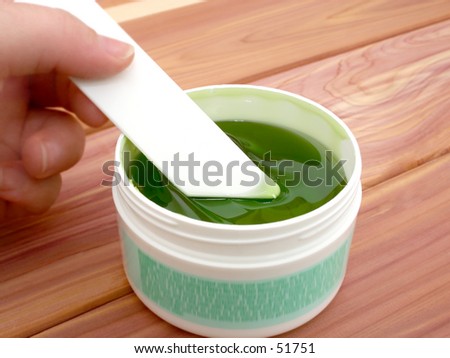 Jar of sticky green hair remover.  Shallow dof with focus on applicator and gel.