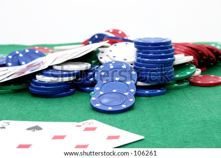 Poker chips and cards on a green felt top table.  Focus on blue chip in middle.