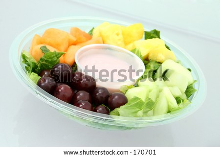 Fruit tray and yogurt on a glass table top.