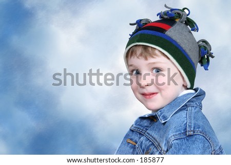 Four year old boy in crazy looking winter cap and a denim jacket.