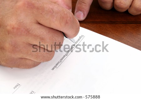 Man's hand signing contract.  Line reads 