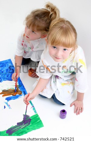 Two young girls painting on the floor. Shot in studio.