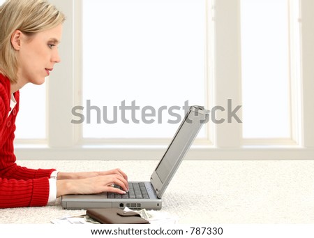 Casual woman in red sweater paying bills online at home.  Space for copy to right.