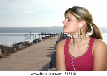 Young woman listening to music outside by the lake.