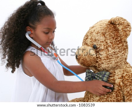 Adorable young girl giving large bear a health check up with toy stethoscope. Shot in studio over white.