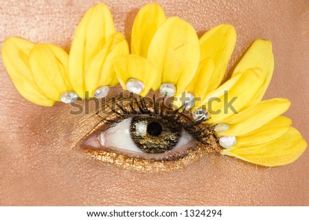 Focus on center eye.  Woman\'s eye decorated in yellow flowers and gold eyeliner.