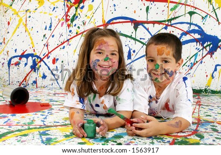 Adorable boy and girl covered in paint lying on splattered paint background