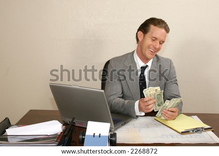 Attractive thirties businessman at desk counting cash.  USD.