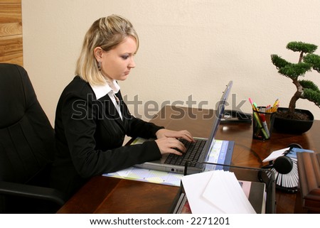 Woman at office desk working on laptop.