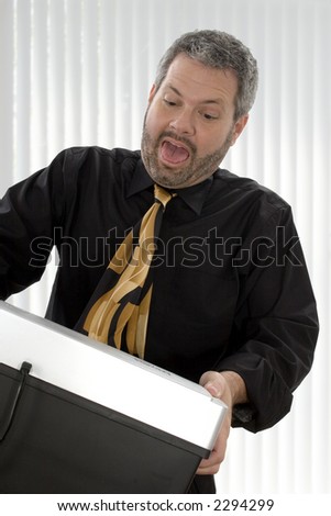 Fourty something business man with tie stuck in paper shredder.