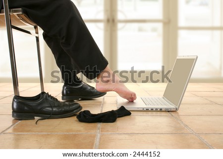 Man\'s bare foot working on laptop.