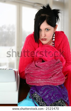 Retail worker with bundle of formal dresses to be hung up.