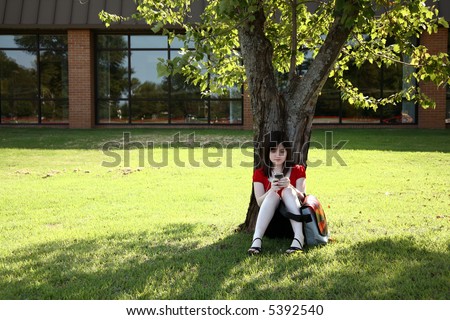 Beautiful Teen girl relaxing under tree with digital music and video after school.