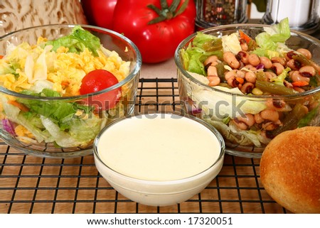 Glass bowl of black eye pea salad and garden salad with ranch dressing in kitchen or restaurant.