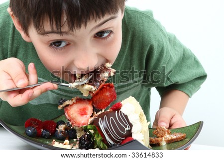 Adorable six year old boy eating glazed fruit cheesecake.