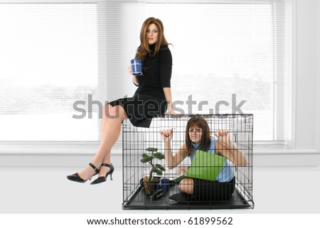 Woman at office in cage looking stressed while woman takes coffee break on top of cage.
