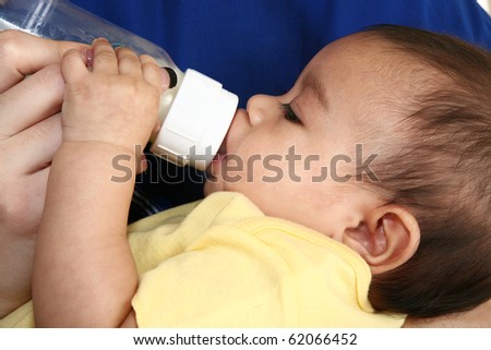 Woman feeding beautiful hispnaic infant a bottle of formula.