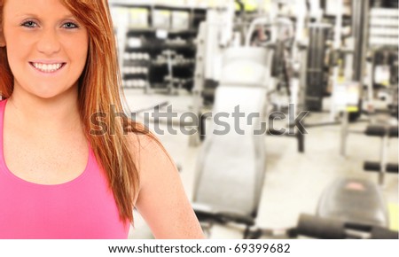 Attractive young woman with ginger hair and pink workout clothes working at fitness store.