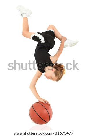 Young girl child balancing upsidedown on top of basketball in uniform over white.