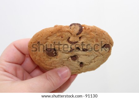 Hand holding a large chocolate chip cookie.