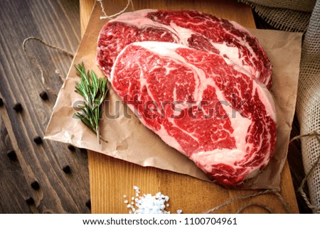 Similar – Image, Stock Photo Two raw marbled rib-eye steak on cutting board with rosemary, garlic and green pepper