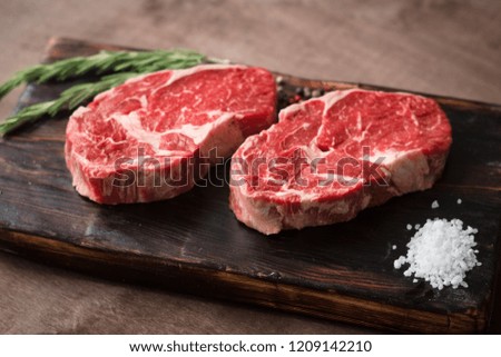 Similar – Image, Stock Photo Two raw marbled rib-eye steak on cutting board with rosemary, garlic and green pepper