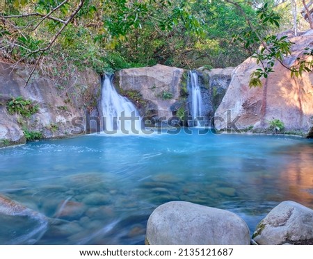 In the rainforest near Rincon National Park, the twin Las Chorreras Waterfalls and the beautiful blue logoon are surrounded by volcanic rock walls and green foliage. Stockfoto © 
