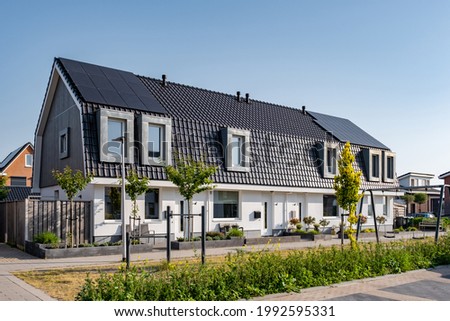 Newly build houses with solar panels attached on the roof against a sunny sky Close up of new building with black solar panels. Zonnepanelen, Zonne energie, Translation: Solar panel, , Sun Energy