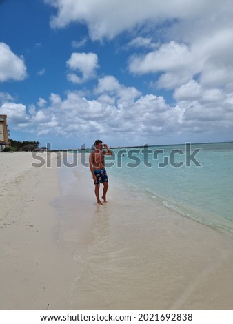 Palm Beach Aruba Caribbean, white long sandy beach with palm trees at Aruba Antilles, young man mid age on the beach in swim short relaxing Foto d'archivio © 